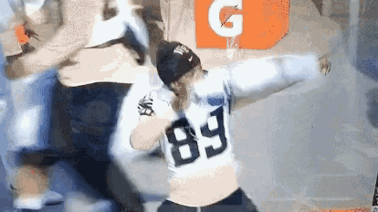a man wearing a jersey with the number 89 on it is standing in front of a gatorade bottle .