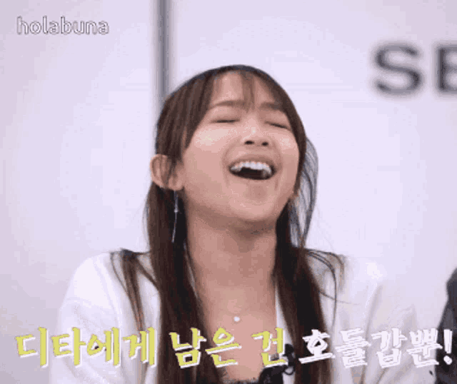 a woman is laughing in front of a sign that says hola buna