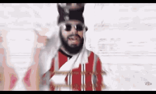 a man with a beard and sunglasses is wearing a red and white striped shirt .