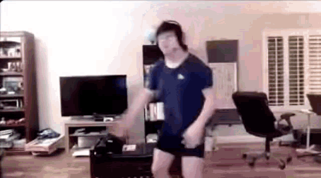 a man is dancing in a living room while wearing headphones .
