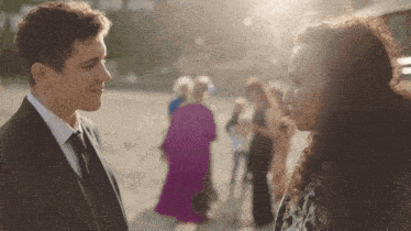 a man in a suit and tie stands next to a woman