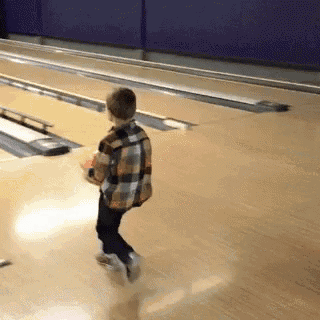a young boy is playing bowling on a bowling alley