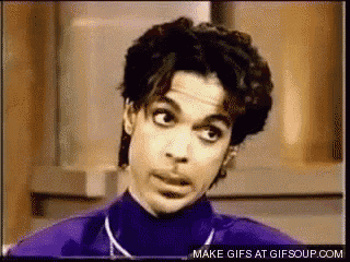prince is wearing a purple turtleneck and necklace and making a funny face .