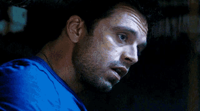 a close up of a man 's face in a blue shirt with his mouth open .