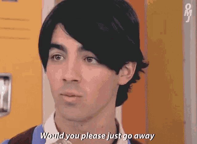a young man with black hair is talking to another young man in a school locker room .