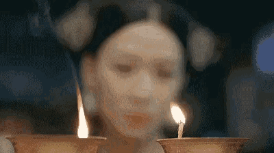 a woman with a mask on her face is holding two candles in her hands .