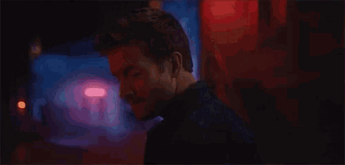 a man in a black jacket is walking down a dark street .