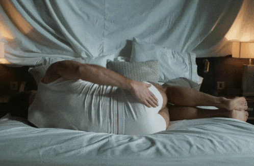 a man in underwear is laying on a bed with his legs crossed