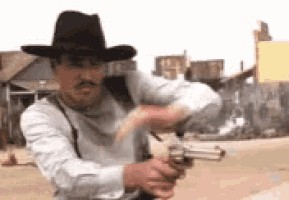 a man in a cowboy hat is pointing a gun at something .