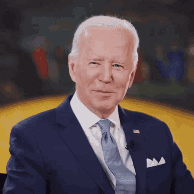 a man in a blue suit and tie is smiling for the camera