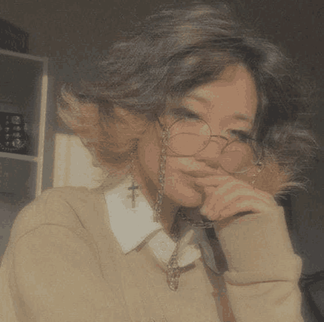 a girl with short hair is wearing glasses and a sweater .