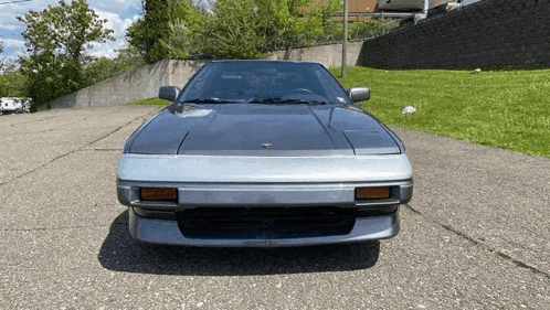 a silver sports car is parked on the side of the road .