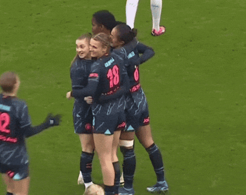 a group of female soccer players are hugging each other with one wearing the number 12