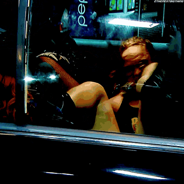 a man is sitting in a car with a pepsi bottle in the background