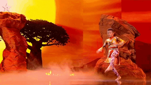 a man in a costume is dancing on a stage with a tree in the background