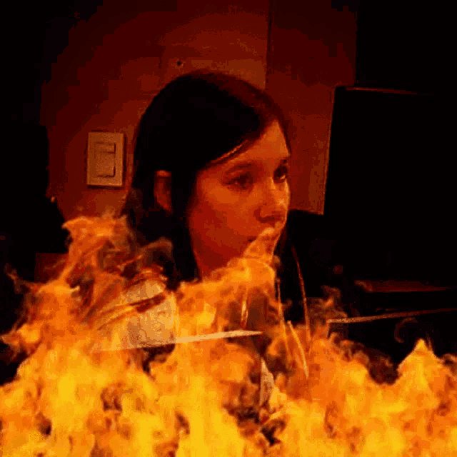 a woman is surrounded by flames while looking at a monitor