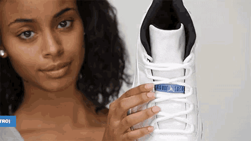 a woman is holding a pair of white shoes with a blue jordan logo