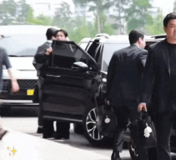 a man in a suit carrying a briefcase is walking towards a car