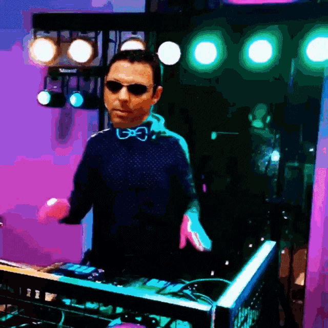 a man wearing sunglasses and a bow tie is playing music on a mixer