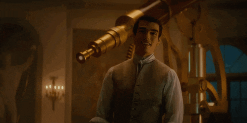 a man stands in front of a telescope and smiles