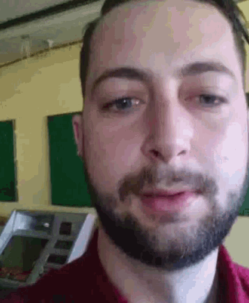a close up of a man 's face with a beard and a red shirt