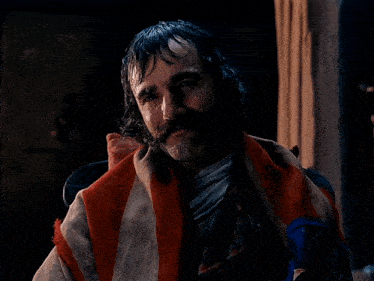 a man with wet hair and a beard is wrapped in a blanket