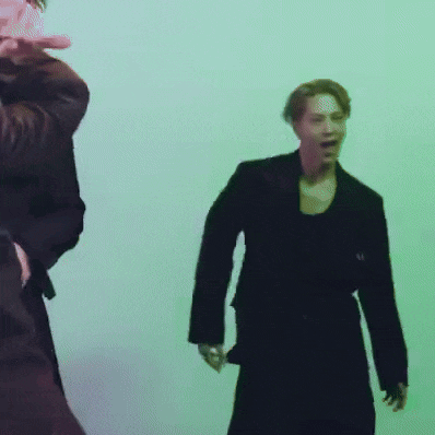 a man in a black suit is standing next to another man