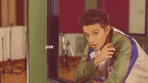 a young man is looking out of a window in a room .