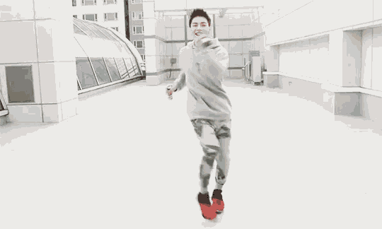 a young man is dancing on a rooftop with his arms outstretched .