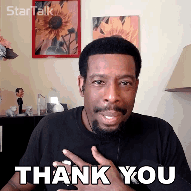 a man in a black shirt is giving a thank you gesture