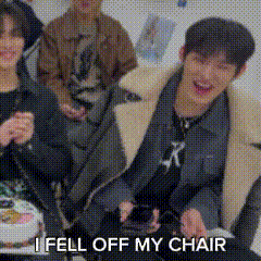 a group of young men are sitting on a couch with a cake and the words `` i fell off my chair '' above them .