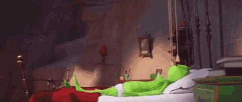 a green cartoon character is sitting on a bed in a bedroom .