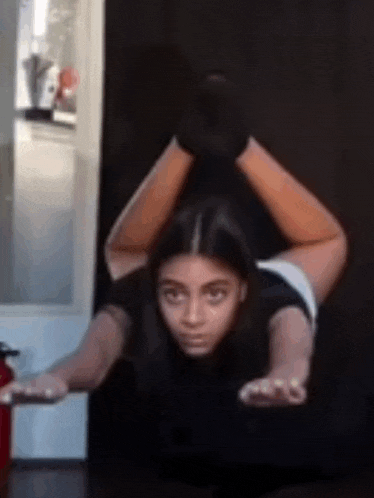a woman is doing a yoga pose with her legs crossed and a fire extinguisher in the background .