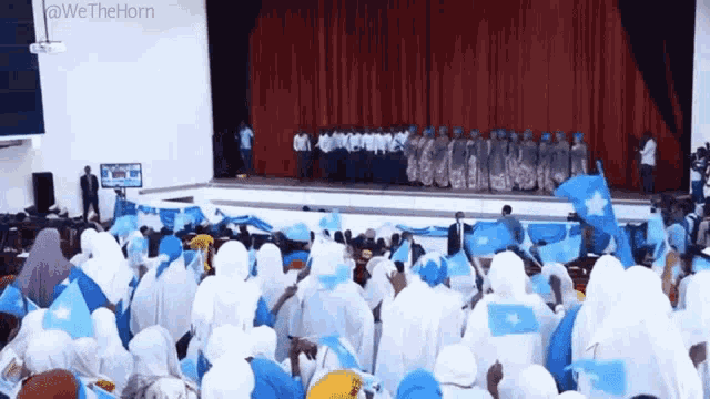 a crowd of people are standing in front of a stage holding flags