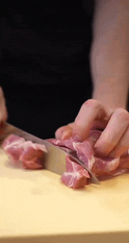 a person is cutting a piece of meat on a cutting board