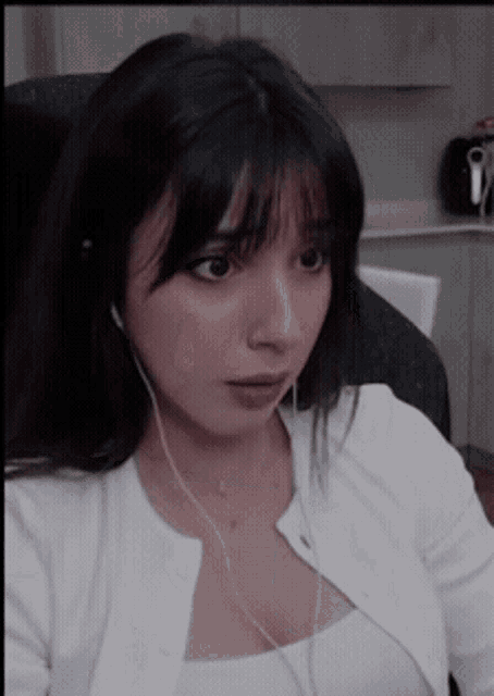 a woman wearing headphones and a white shirt is looking at something