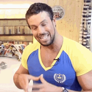 a man wearing a blue and yellow shirt with a laurel wreath on it is smiling