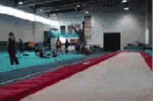 a blurry picture of a trampoline in a gym with people in the background .