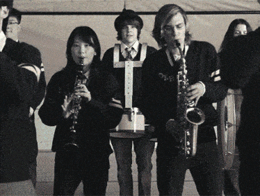 a man playing a saxophone and a woman playing a clarinet with the word dh on their sweater