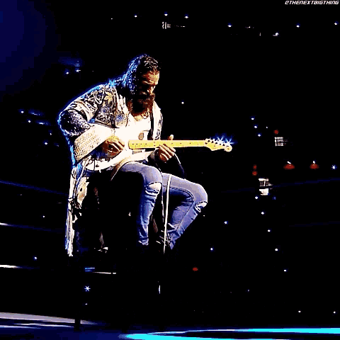 a man with a beard is playing a guitar on a stage with the name elias above him