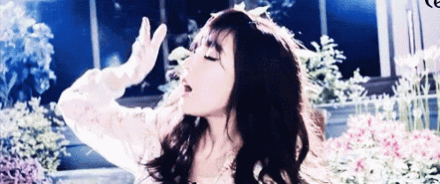a woman is standing in front of a window with her hands in the air and her mouth open .