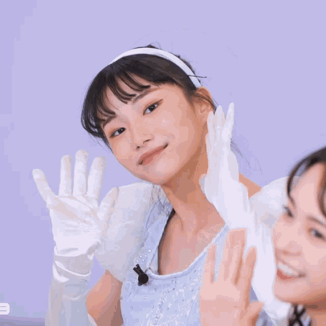 a girl wearing a blue dress and white gloves blowing a kiss