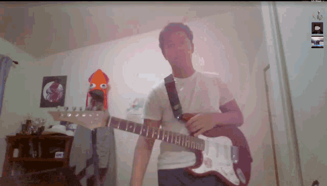 a man playing a guitar in front of a wall with a squid on it