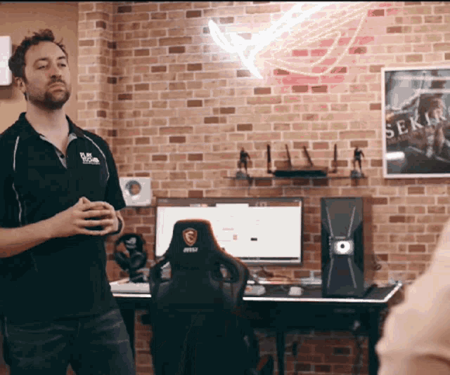a man stands in front of a desk with a msi gaming chair
