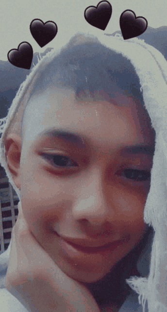 a young boy wearing a white scarf and black hearts on his head