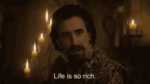 a man with a beard is smiling and says life is so rich