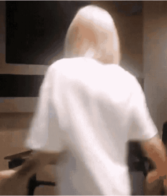 a woman in a white t-shirt is standing in a room .
