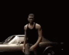 a man flexing his muscles in front of a car .