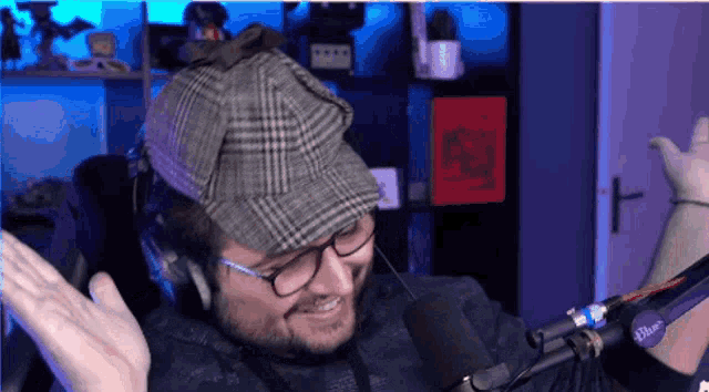 a man wearing a hat and headphones stands in front of a microphone