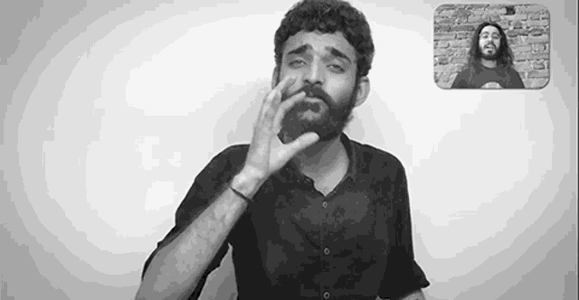 a man with a beard is making a funny face in a black and white photo while another man looks on .